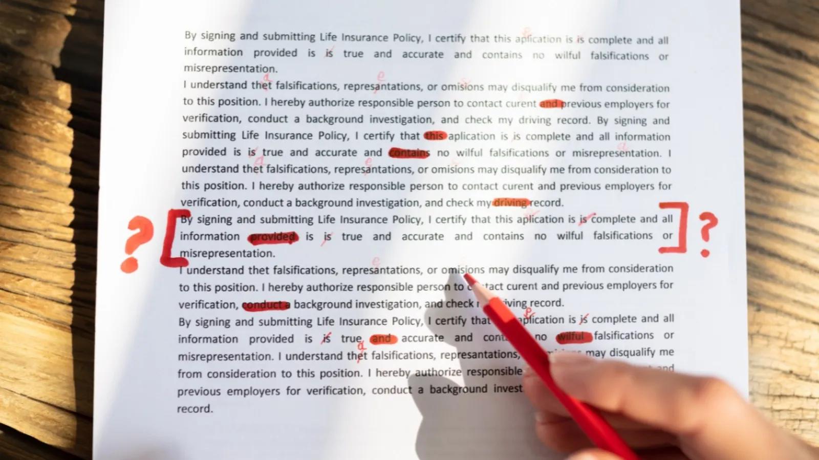 A printed page marked up in red pen, with corrections and query marks through the text and a hand holding a red pencil over it.