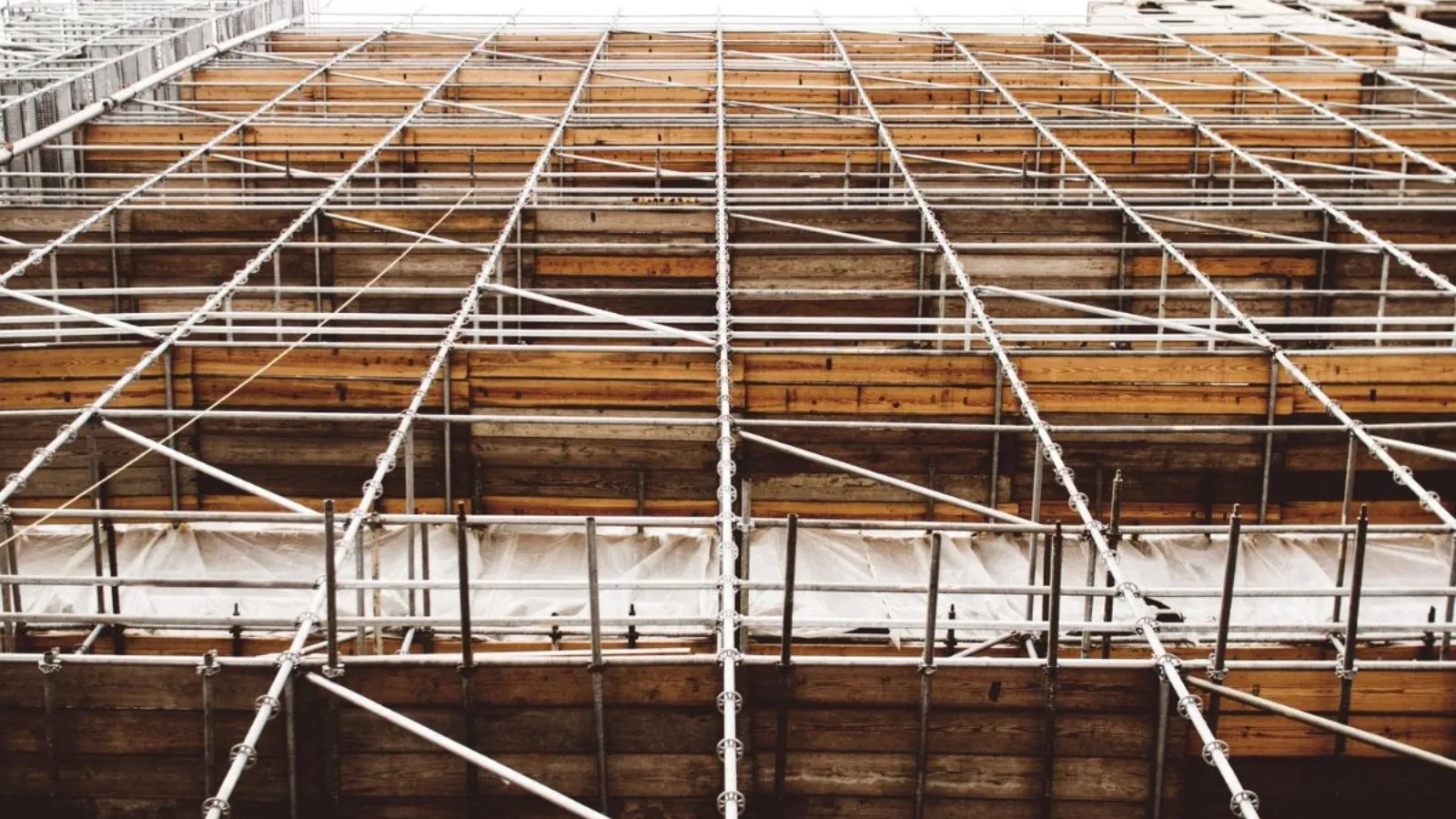 Scaffolding photographed from below, its poles and diagonal braces continuing past the top of the frame.