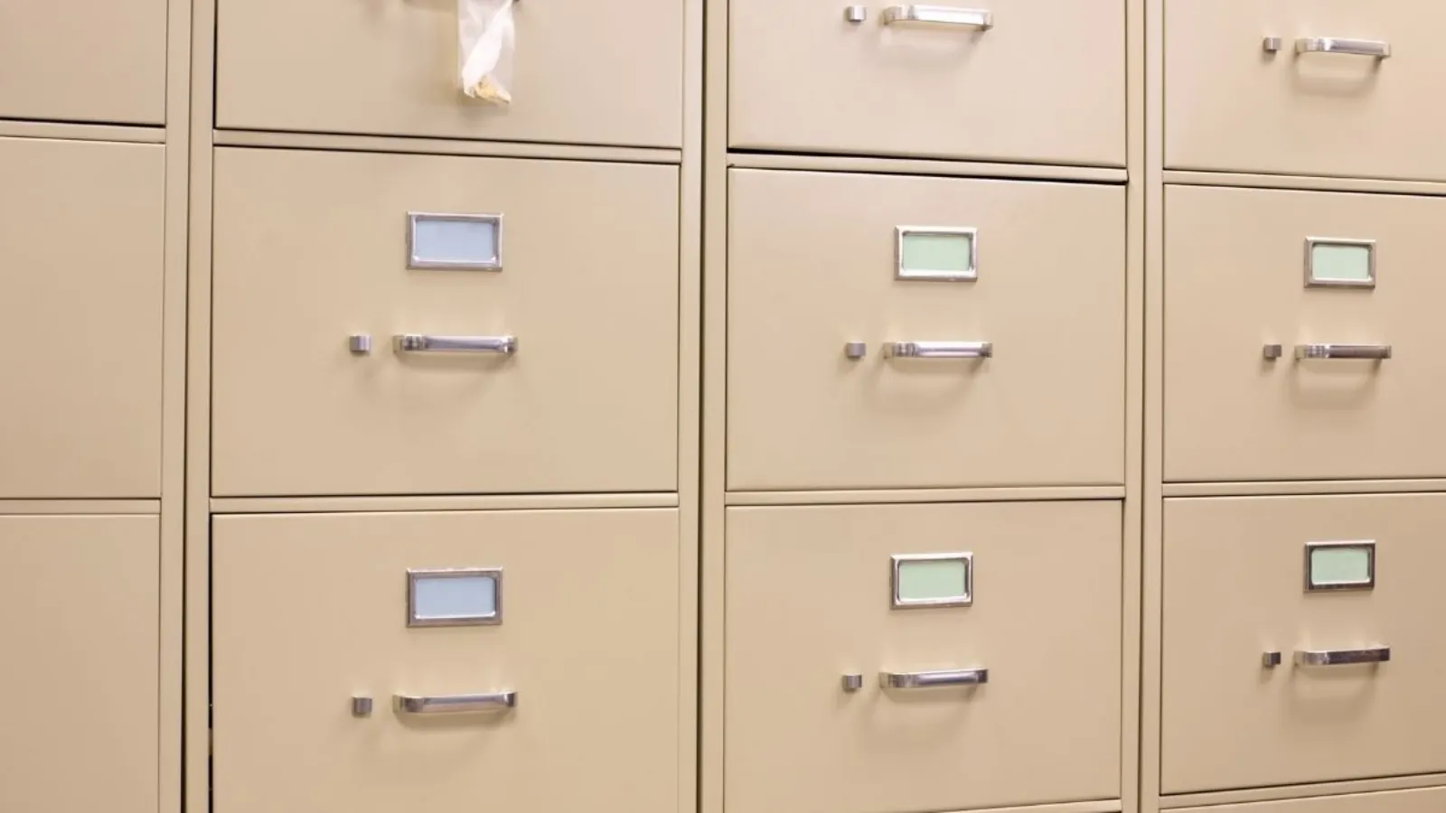 A wall of beige metal filing cabinets, every drawer closed and the label holders on them blank.